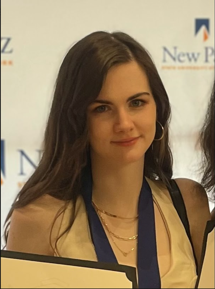 Photo of a student smiling at the camera in front of a light background